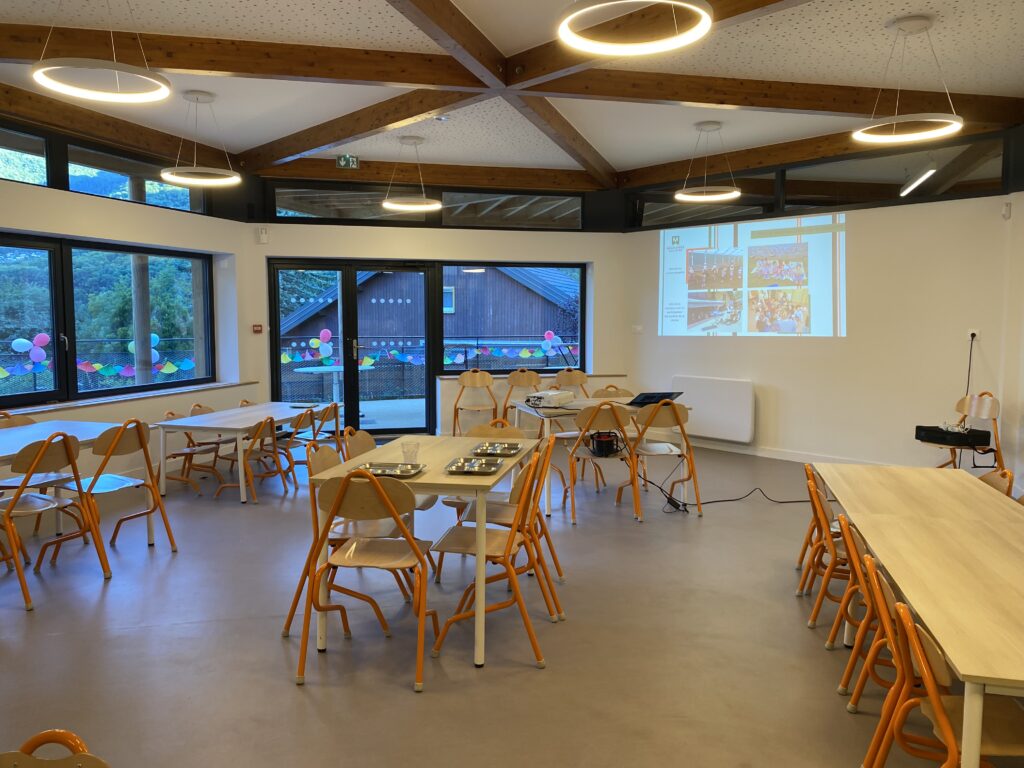 Intérieur d'une salle dédiée à l'accueil des enfants avec des tables et des chaises