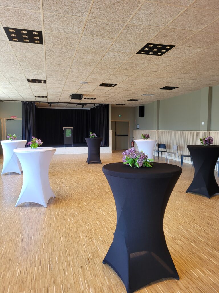 Intérieur de la salle des fêtes d'Aussois avec des mange-debout noir et blanc